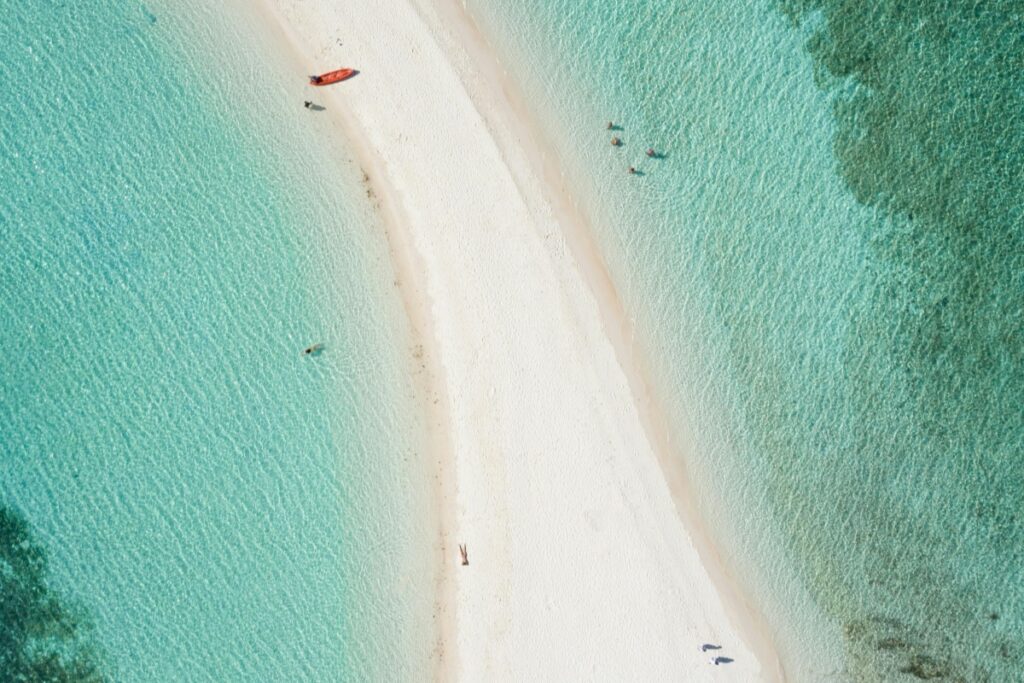 Ang larawan ay nagpapakita ng isang magandang beach na may puting buhangin at malinaw at berdeng-kulay na tubig. Mayroong ilang tao na nakikita sa tubig at sa dalampasigan, pati na rin ang isang pulang bangka. Katulad ng beach na madaling mapansin at ma-appreciate dahil sa kagandahan nito, dapat mong gamitin ang YouTube para sa iyong negosyo. Dahil sa YouTube, maaari mong maabot ang malawak na audience, maipakita ang iyong produkto o serbisyo, at mapalawak ang iyong negosyo sa pamamagitan ng paglulunsad ng mga engaging na video.